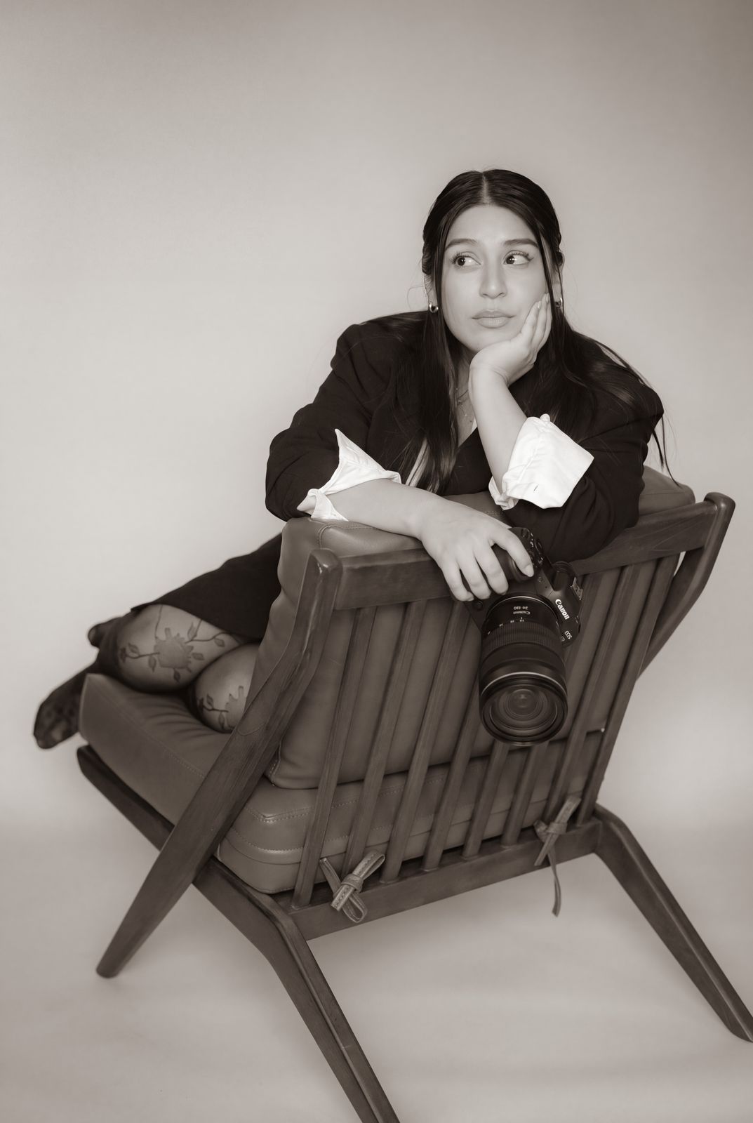 Brenda seated backwards on a chair, holding her camera
