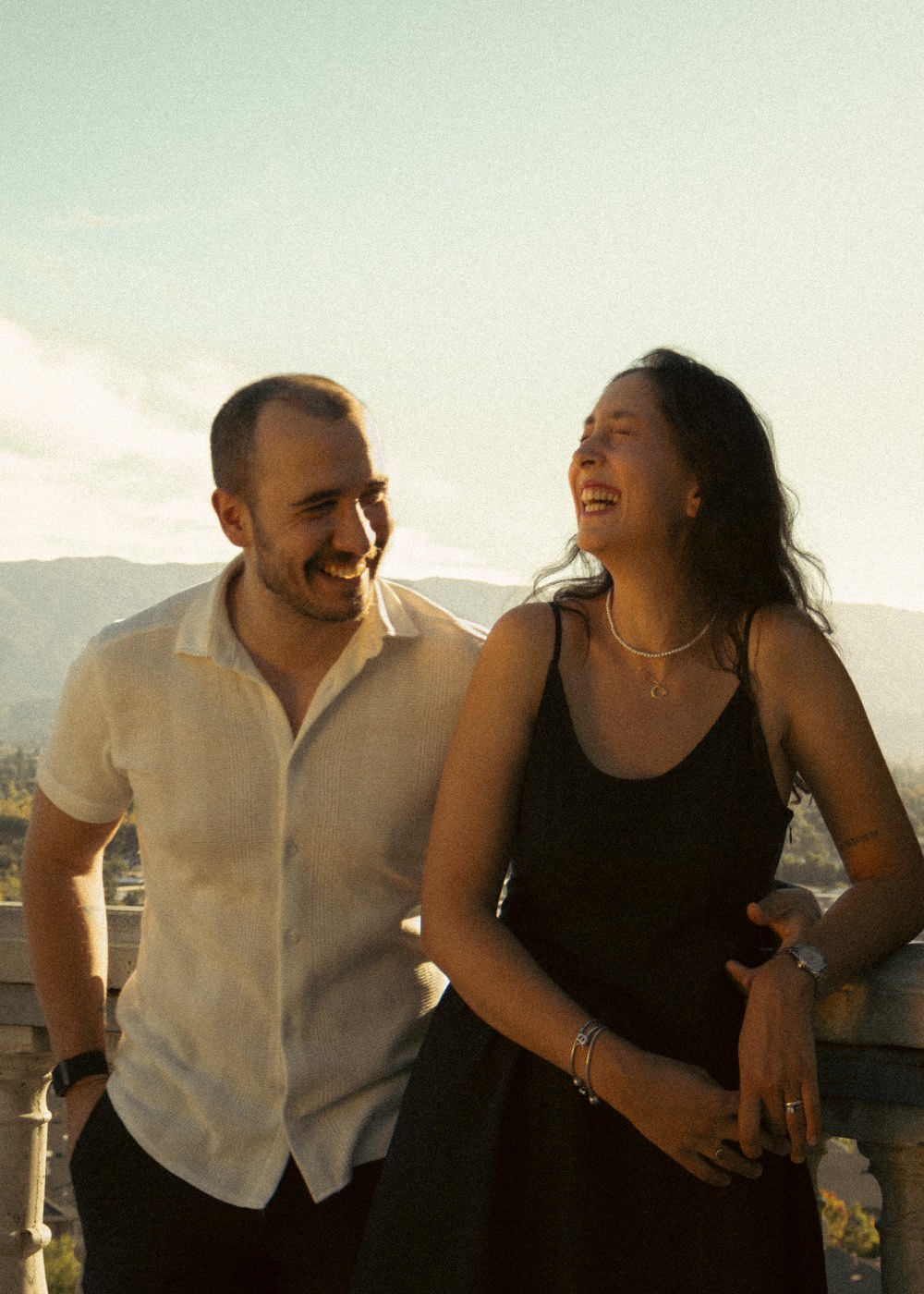 Couple laughing on a terrace above the hills